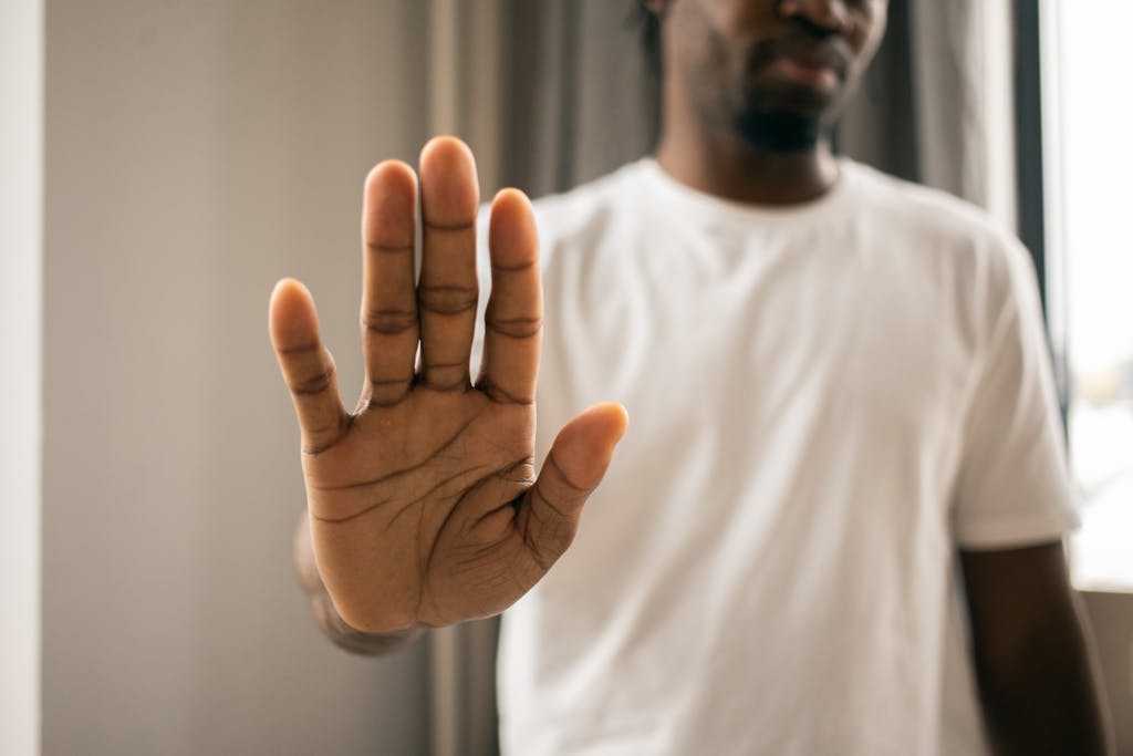 Close-up of a man with a hand gesture expressing stop or refusal indoors